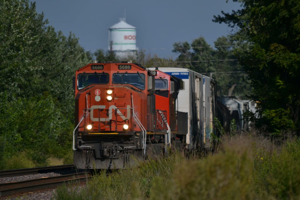 Canadian freight train passing through Boone, Iowa, surrounded by lush greenery.